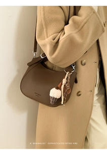 Brown litchi grain leather bucket bag with plush charm styled on a wool coat