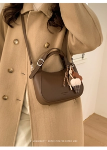 Detail view of brown litchi leather bucket bag with cute heart and ribbon charms