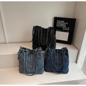 Detailed view of vintage denim shoulder bags in three washes with rivets and drawstring details