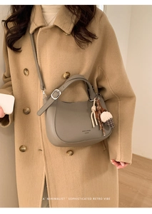 Grey leather bucket bag with top handle and plush ice cream charm shown on a model