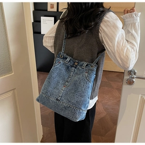Detail of vintage denim tote bag featuring red contrast stitching and pocket accents