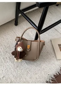 Détail du sac seau marron clair grainé avec fermoir doré et pendentif ourson