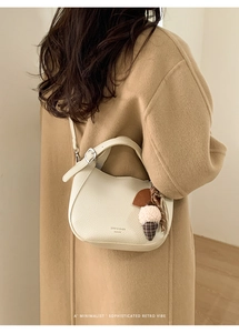 Close-up of off-white lychee texture crossbody bag with cute plush ice cream pendant