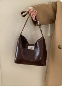 Detail of deep brown glossy leather shoulder bag with silver turn-lock and vintage style
