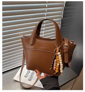 Detail of vintage brown bucket bag with colorful wooden bead charm and brand logo