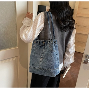 Detail of vintage denim tote bag showing pockets and washed fabric texture on shoulder