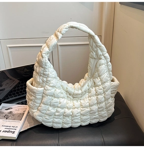 Détail d'un sac hobo en nylon crème avec texture matelassée douce et une poche latérale