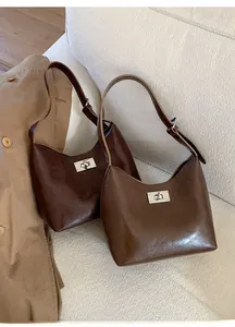 Detailed close-up of brown leather handbags with vintage metal twist locks on a sofa