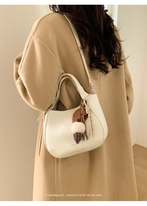 Detail of white leather bucket bag with pink ice cream charm and braided knot accessory