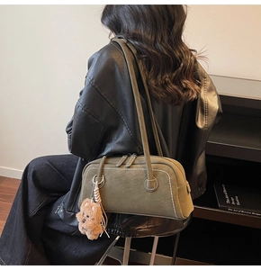 Olive green suede shoulder bag detail with white stitching and plush bear charm