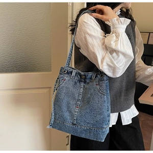 Detail showing the denim tote bag with jeans waist design and red stitching details