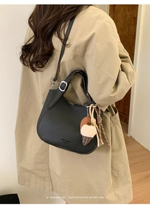 Detail of black lychee grain leather bucket bag with silver buckle and plush charm