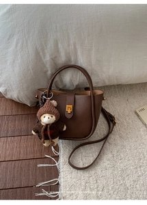 Détail du sac seau en cuir grainé marron foncé avec fermoir doré et pendentif ours