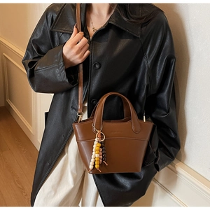 Detail of a brown trapezoid handbag with colorful wooden beads and a detachable shoulder strap
