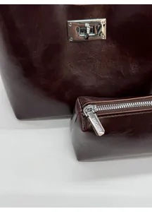 Close-up of deep wine red leather bag texture with silver metallic twist lock and hardware