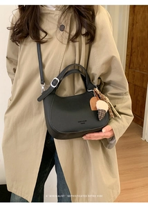 Detail of black pebbled leather hobo bag with adjustable strap on a female model