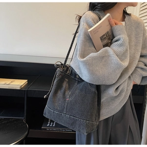 Detail showing vintage dark grey denim shoulder bag with white stitching and pocket design