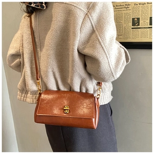 Dettaglio della borsa vintage in pelle caramello con chiusura a scatto dorata e tracolla