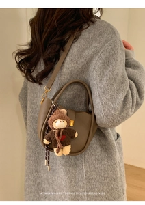 Sac cabas rétro en daim marron avec breloque ours porté sur un manteau gris