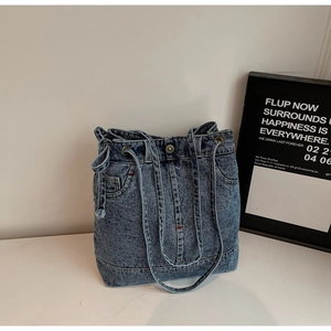 Detailed view of dark blue washed denim tote bag with industrial stitching and retro metal eyelets
