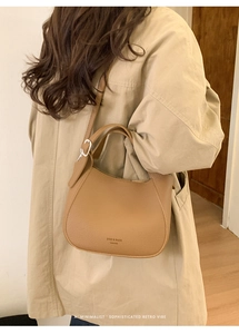 Detail of trendy brown leather saddle bag with adjustable strap and textured finish