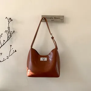 Close-up of vintage brown leather underarm bag featuring a metallic twist-lock closure