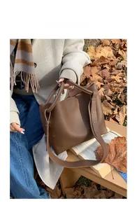 Outdoor model display of coffee brown leather bucket bag with wide shoulder strap