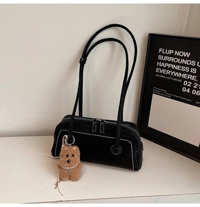 Detail view of black underarm bag with white contrast stitching and bear charm accessory