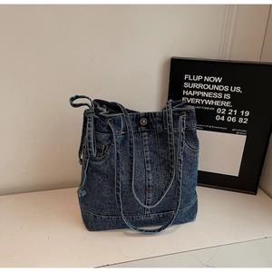 Close-up of deep blue denim tote bag featuring utility cargo pockets and metal buckle