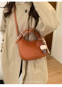 Detail showing litchi grain leather texture and ice cream charm on brown bucket bag