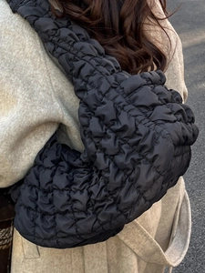 Sac fourre-tout noir matelassé tendance porté avec un élégant manteau d'hiver