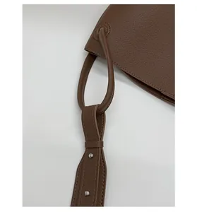 Detailed close-up of brown litchi pattern leather bag with silver metal rivet hardware