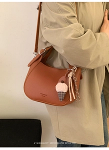 Detail of brown lychee texture leather bucket bag with ice cream plush charm and logo