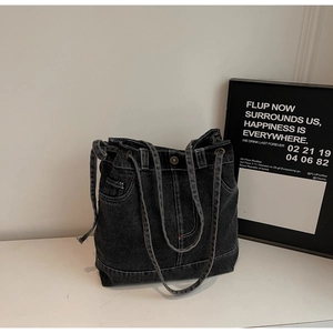 Detailed close-up of dark denim tote bag featuring white contrast stitching and side drawstrings
