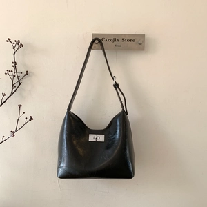 Detail showing the glossy leather texture and silver twist lock on the black shoulder bag