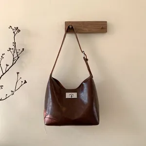 Detail of dark brown leather hobo bag featuring silver twist lock and adjustable strap