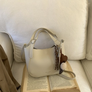 Close-up of cream leather bucket bag with textured grain and decorative heart charm