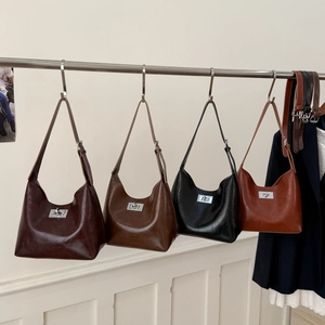 Close-up of retro crescent shoulder bags in dark brown, coffee, black, and caramel faux leather