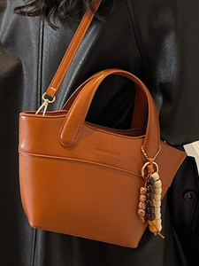 Vintage cognac leather bucket bag with beaded charm and crossbody strap for women