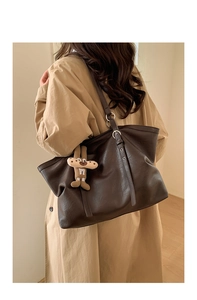 Detail of dark brown leather tote bag with silver hardware and a cute rabbit charm