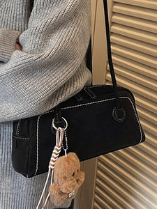 Minimalist black underarm bag with white contrast stitching and plush bear charm