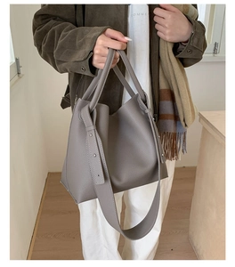 Gray lychee grain leather bucket bag shown on model with shoulder strap for daily commuting