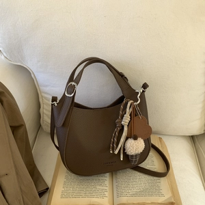 Close-up of deep brown litchi pattern bucket bag with decorative charms and brand logo