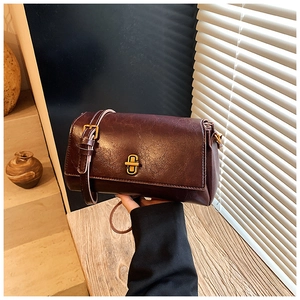 Dettaglio della borsa in pelle bordeaux con finitura lucida e chiusura a croce dorata