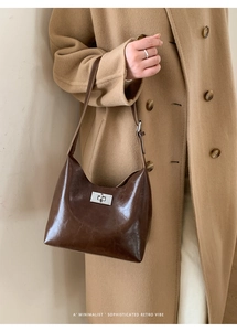 Detail of minimalist dark brown leather shoulder bag with polished silver twist lock