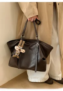 Detailed view of dark brown tote bag with leather texture and cute bunny pendant charm
