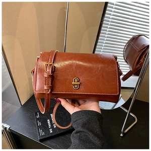 Dettaglio della borsa in pelle marrone vintage con finitura cerata e chiusura a scatto dorata