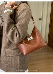 Retro brown leather shoulder bag styled with a brown herringbone wool coat in a minimalist home