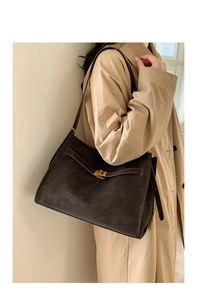 Detailed view of vintage matte leather tote bag with gold swivel clasp on model outfit