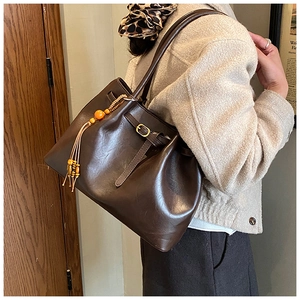 Détail d'un grand sac cabas vintage marron foncé avec pompon en perles et bandoulière